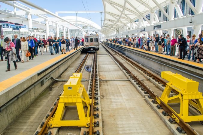 The passengers on the right wait their turn for a ride on the A line, while those on the left celebrate a smooth inaugural ride.